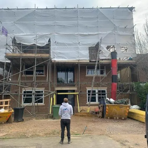 Roofer standing in front of a scaffolded house during a re-roof in Essex
