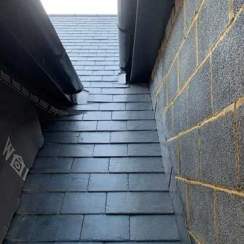 Slate roof abutting a brick wall with lead flashing