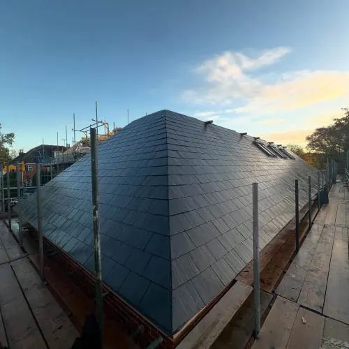 Dark slate roof on a new build with scaffolding at dusk
