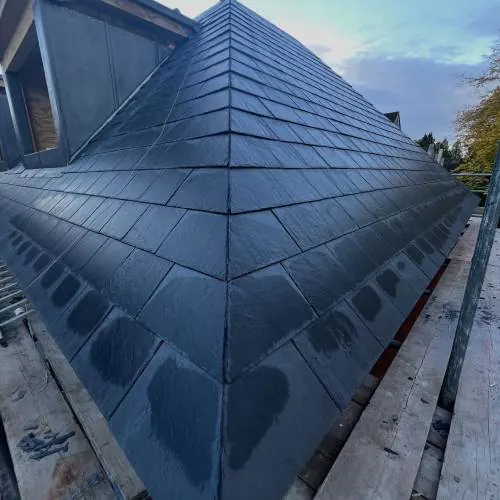 New slate hipped roof on a large house with scaffolding