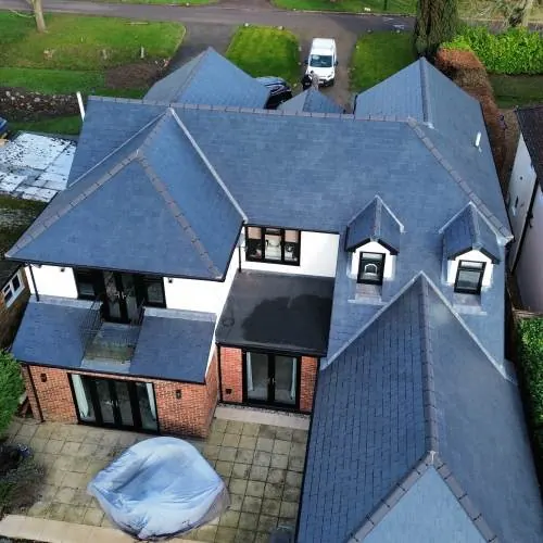Drone view of a large detached home with multiple slate roof pitches